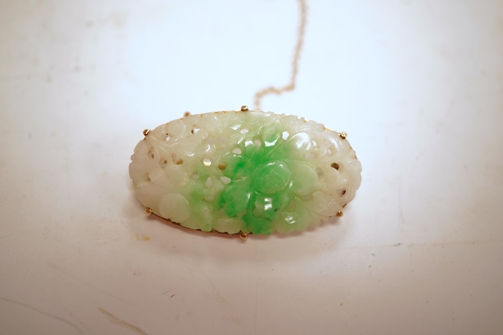 A jadeite brooch, set with an oval jadeite of mottled green and white, carved to depict flowers, mounted in 9ct gold, length 3.2cm, British hallmarks, maker's mark for Cropp & Farr, gross weight approximately 4.5 grams,
